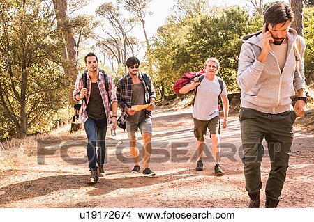 Picture - Man talking on smartphone whilst hiking with friends in forest, Deer Park, Cape Town, South Africa. Fotosearch