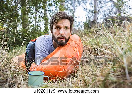 Stock Photo - Man watching from sleeping bag in forest, Deer Park, Cape Town, South Africa. Fotosearch