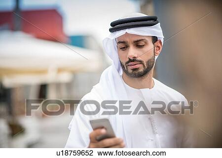 Man wearing traditional middle eastern clothing reading smartphone text, Dubai, United Arab Emirates View Large Photo Image Stock Image - Man wearing traditional middle eastern clothing reading smartphone text, Dubai, United Arab Emirates. Fotosearch