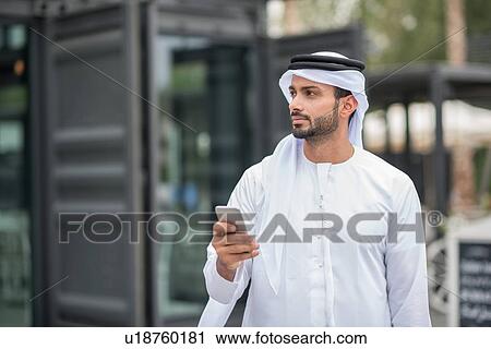 Man wearing traditional middle eastern clothing using smartphone, Dubai, United Arab Emirates View Large Photo Image Stock Image - Man wearing traditional middle eastern clothing using smartphone, Dubai, United Arab Emirates. Fotosearch