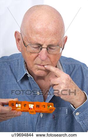 Picture - Man with pill organiser. Fotosearch