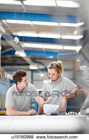 Stock Photo - Manager advising female worker on production line in factory. Fotosearch