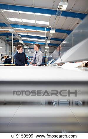 Stock Photo - Manager and factory worker discussing work in roller blind factory. Fotosearch