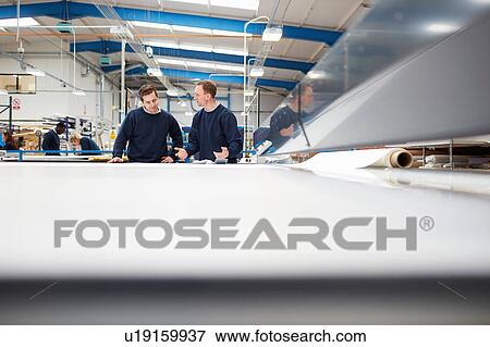 Stock Photo - Manager mentoring worker on production line in roller blind factory. Fotosearch