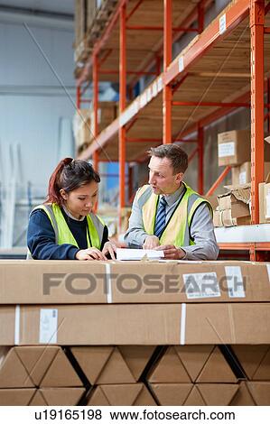Stock Photo - Manager training female factory worker in factory warehouse packing. Fotosearch