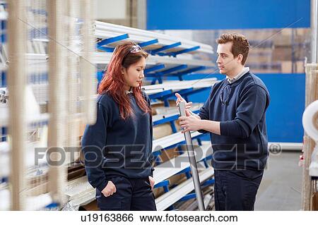 Stock Photograph - Manger mentoring young female worker in roller blind factory. Fotosearch