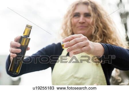 Stock Image - Market trader with bottle of olive oil. Fotosearch
