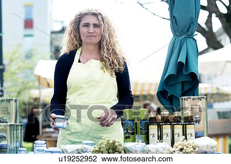 Stock Image - Market trader with variety of olive oil produce. Fotosearch