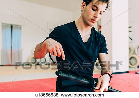 Stock Photo - Martial artist in gym preparing sword. Fotosearch