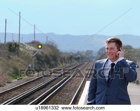 Mature businessman standing on train platform, using smartphone View Large Photo Image Stock Image - Mature businessman standing on train platform, using smartphone. Fotosearch