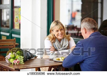 Stock Photograph - Mature couple on date chatting at sidewalk cafe table. Fotosearch