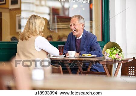 Mature couple on date laughing together at sidewalk cafe table View Large Photo Image Picture - Mature couple on date laughing together at sidewalk cafe table. Fotosearch