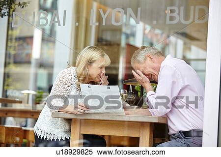 Stock Photography - Mature dating couple giggling at restaurant table. Fotosearch