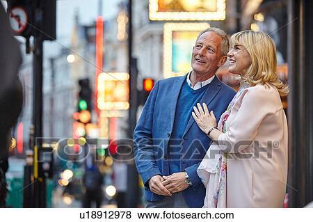 Stock Photo - Mature dating couple looking up from city street at dusk, London, UK. Fotosearch