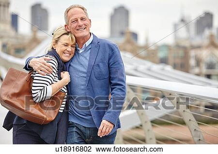 Stock Image - Mature dating couple strolling across Millennium Bridge, London, UK. Fotosearch
