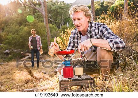 Mature man frying on camping stove in forest, Deer Park, Cape Town, South Africa View Large Photo Image Stock Photo - Mature man frying on camping stove in forest, Deer Park, Cape Town, South Africa. Fotosearch
