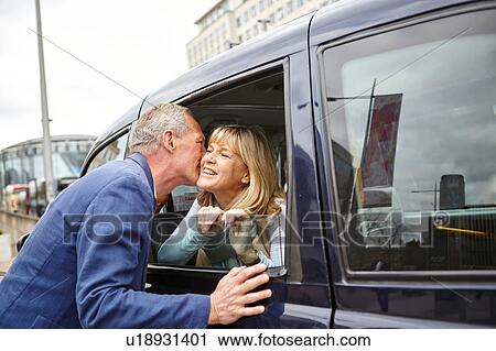 Mature man kissing date on cheek at black cab window View Large Photo Image Stock Image - Mature man kissing date on cheek at black cab window. Fotosearch