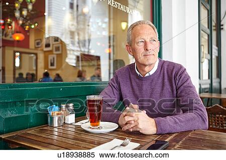 Mature man looking out from sidewalk cafe table View Large Photo Image Stock Photography - Mature man looking out from sidewalk cafe table. Fotosearch