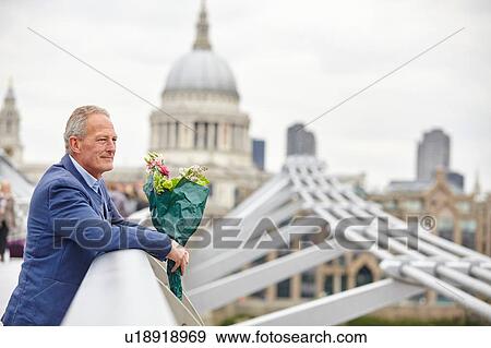 Stock Photo - Mature man with bouquet waiting on Millennium Bridge, London, UK. Fotosearch