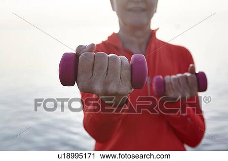 Mature woman beside water, exercising with hand weights, mid section View Large Photo Image Stock Image - Mature woman beside water, exercising with hand weights, mid section. Fotosearch