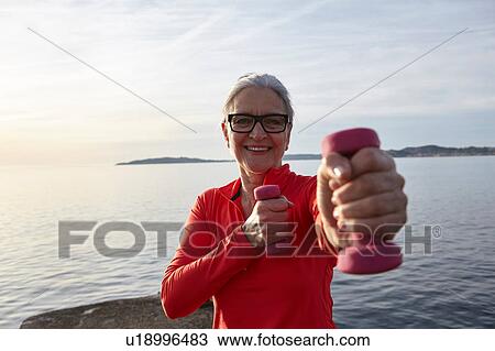 Mature woman beside water, exercising with hand weights, smiling View Large Photo Image Stock Image - Mature woman beside water, exercising with hand weights, smiling. Fotosearch