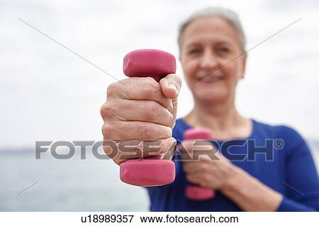 Stock Photo - Mature woman exercising with hand weights. Fotosearch