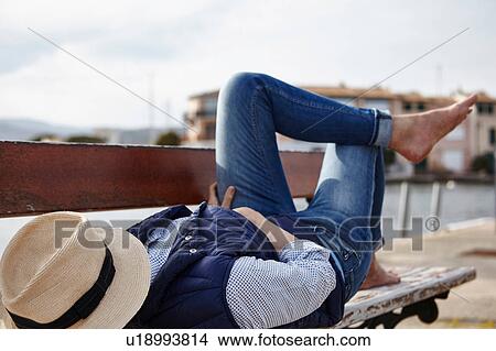 Mature woman lying on bench, hat covering face View Large Photo Image Picture - Mature woman lying on bench, hat covering face. Fotosearch