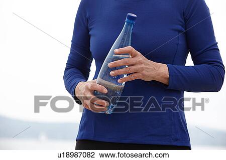 Mature woman outdoors, holding bottle of water, mid section View Large Photo Image Stock Image - Mature woman outdoors, holding bottle of water, mid section. Fotosearch