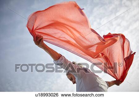 Mature woman outdoors, holding scarf behind her, low angle view View Large Photo Image Stock Photograph - Mature woman outdoors, holding scarf behind her, low angle view. Fotosearch