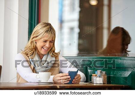 Mature woman reading smartphone text at sidewalk cafe table View Large Photo Image Stock Photo - Mature woman reading smartphone text at sidewalk cafe table. Fotosearch