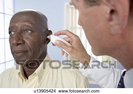 Picture - Measuring ear temperature. Fotosearch