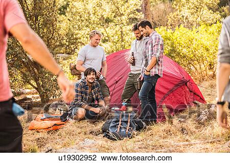 Stock Image - Men preparing food on camping stove in forest, Deer Park, Cape Town, South Africa. Fotosearch