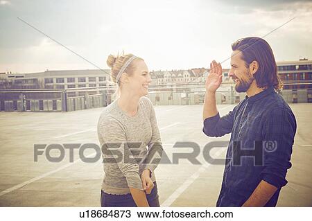Mid adult couple giving high five on rooftop parking lot View Large Photo Image Stock Image - Mid adult couple giving high five on rooftop parking lot. Fotosearch
