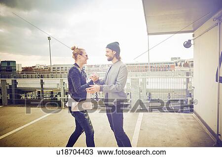 Mid adult couple holding hands and laughing on rooftop parking lot View Large Photo Image Stock Image - Mid adult couple holding hands and laughing on rooftop parking lot. Fotosearch