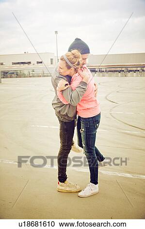 Stock Image - Mid adult couple hugging each other on rooftop parking lot. Fotosearch