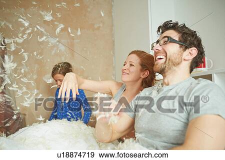 Mid adult couple pillow fighting daughter in bed View Large Photo Image Stock Photo - Mid adult couple pillow fighting daughter in bed. Fotosearch