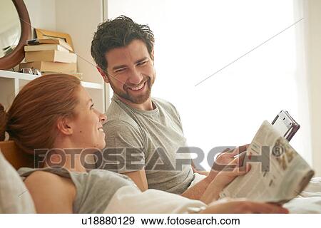 Mid adult couple reading broadsheet and digital tablet in bed View Large Photo Image Stock Photo - Mid adult couple reading broadsheet and digital tablet in bed. Fotosearch