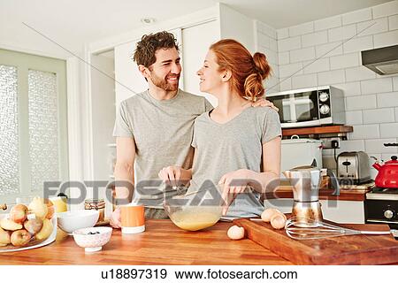 Mid adult couple whisking eggs at kitchen counter for breakfast View Large Photo Image Stock Photo - Mid adult couple whisking eggs at kitchen counter for breakfast. Fotosearch