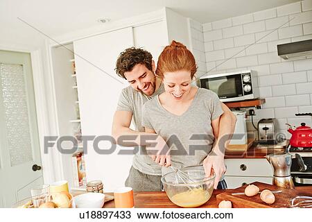 Mid adult couple whisking eggs together at kitchen counter for breakfast View Large Photo Image Stock Image - Mid adult couple whisking eggs together at kitchen counter for breakfast. Fotosearch