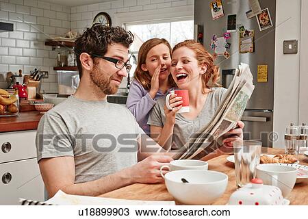 Mid adult man at breakfast table reading newspaper whilst daughter and mother laughing View Large Photo Image Stock Image - Mid adult man at breakfast table reading newspaper whilst daughter and mother laughing. Fotosearch
