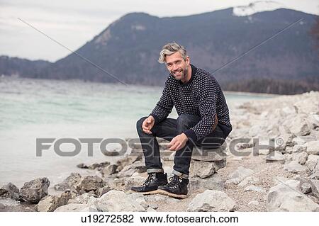 Mid adult man sitting beside lake, German Alps, Germany View Large Photo Image Stock Image - Mid adult man sitting beside lake, German Alps, Germany. Fotosearch