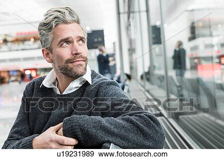 Mid adult man, sitting outdoors, looking away View Large Photo Image Stock Photo - Mid adult man, sitting outdoors, looking away. Fotosearch