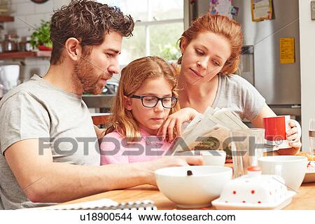 Mid adult parents at breakfast table reading newspaper with daughter View Large Photo Image Picture - Mid adult parents at breakfast table reading newspaper with daughter. Fotosearch