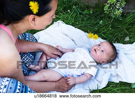 Stock Photo - Mid adult woman and baby son gazing at each other in garden. Fotosearch