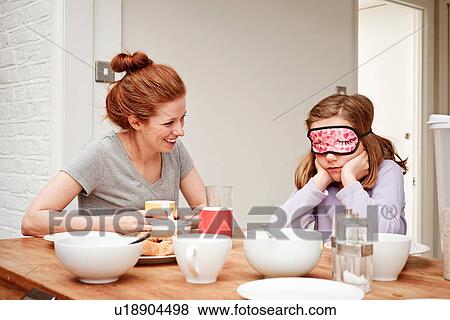 Mid adult woman at breakfast table with daughter wearing sleep mask View Large Photo Image Stock Photo - Mid adult woman at breakfast table with daughter wearing sleep mask. Fotosearch