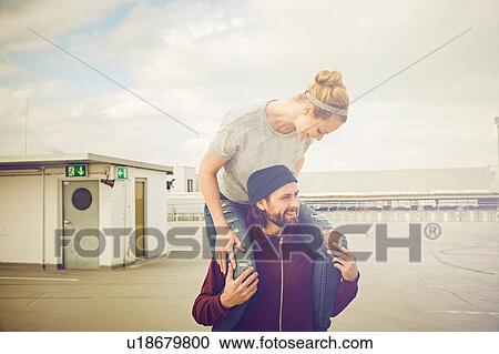 Mid adult woman getting shoulder ride from boyfriend on rooftop parking lot View Large Photo Image Stock Image - Mid adult woman getting shoulder ride from boyfriend on rooftop parking lot. Fotosearch