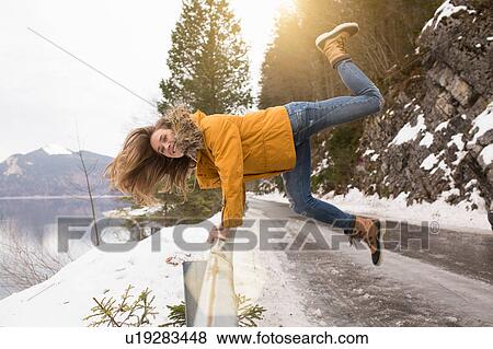 Mid adult woman holding railing by side of road, jumping in air, German Alps, Germany View Large Photo Image Stock Photo - Mid adult woman holding railing by side of road, jumping in air, German Alps, Germany. Fotosearch
