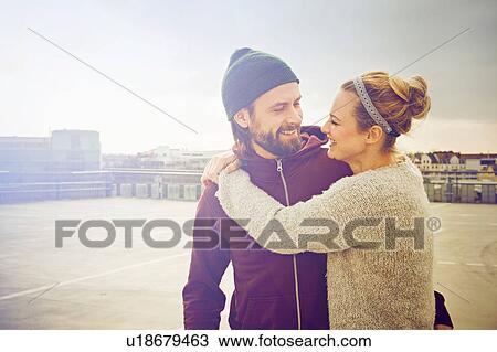 Mid adult woman hugging boyfriend on rooftop parking lot View Large Photo Image Stock Image - Mid adult woman hugging boyfriend on rooftop parking lot. Fotosearch