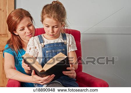 Mid adult woman reading book with daughter on armchair View Large Photo Image Stock Photo - Mid adult woman reading book with daughter on armchair. Fotosearch