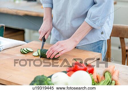 Mid section of woman slicing cucumber View Large Photo Image Stock Photography - Mid section of woman slicing cucumber. Fotosearch